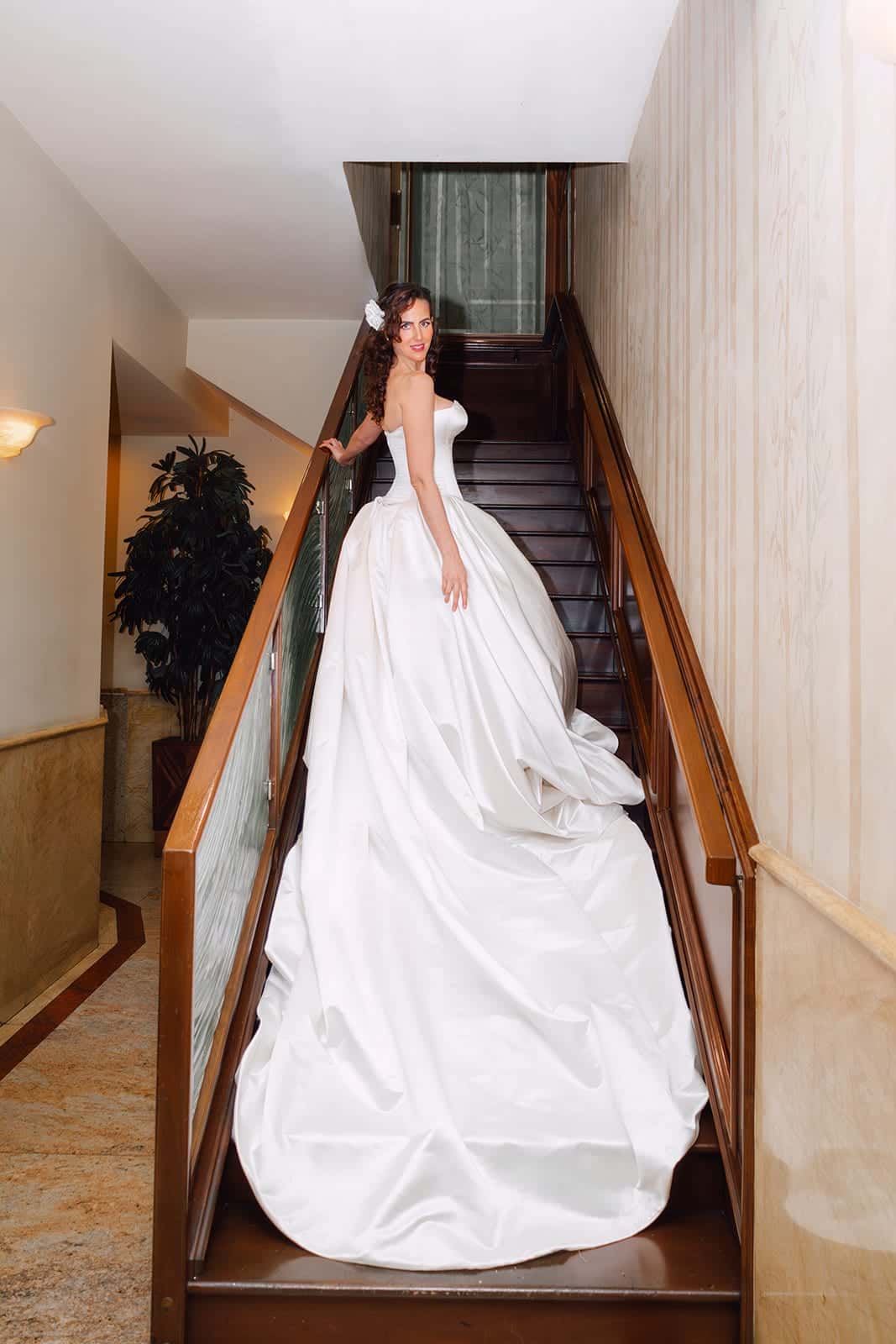 OT Haute Couture silk satin bridal gown with a long train, sweeping down a staircase