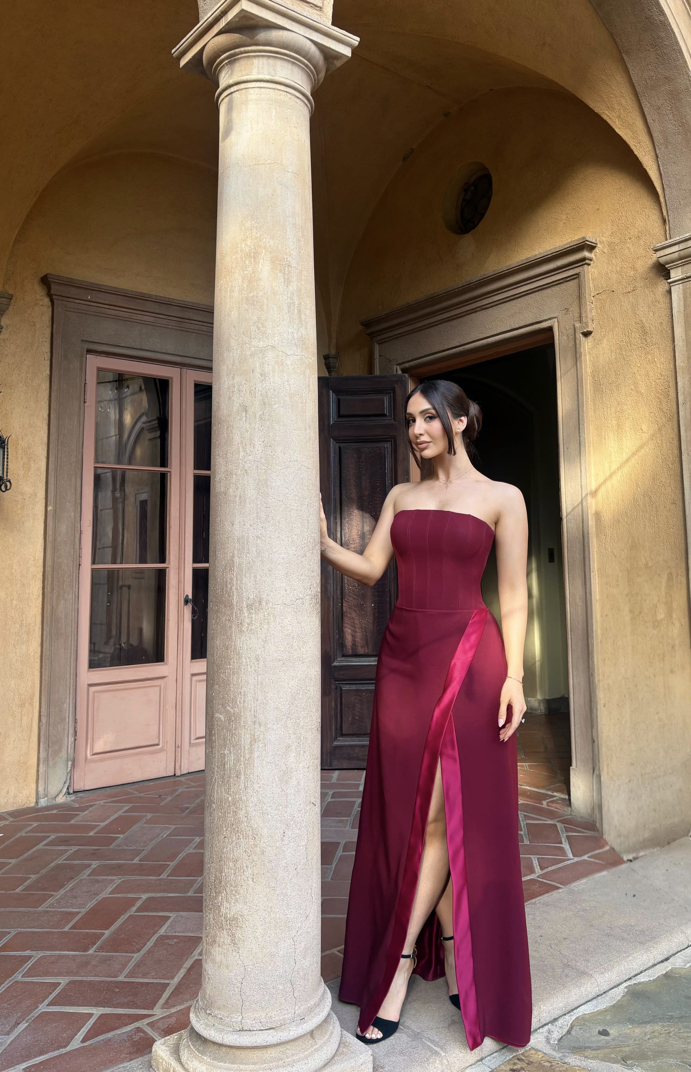 Burgundy strapless evening gown in an architectural setting