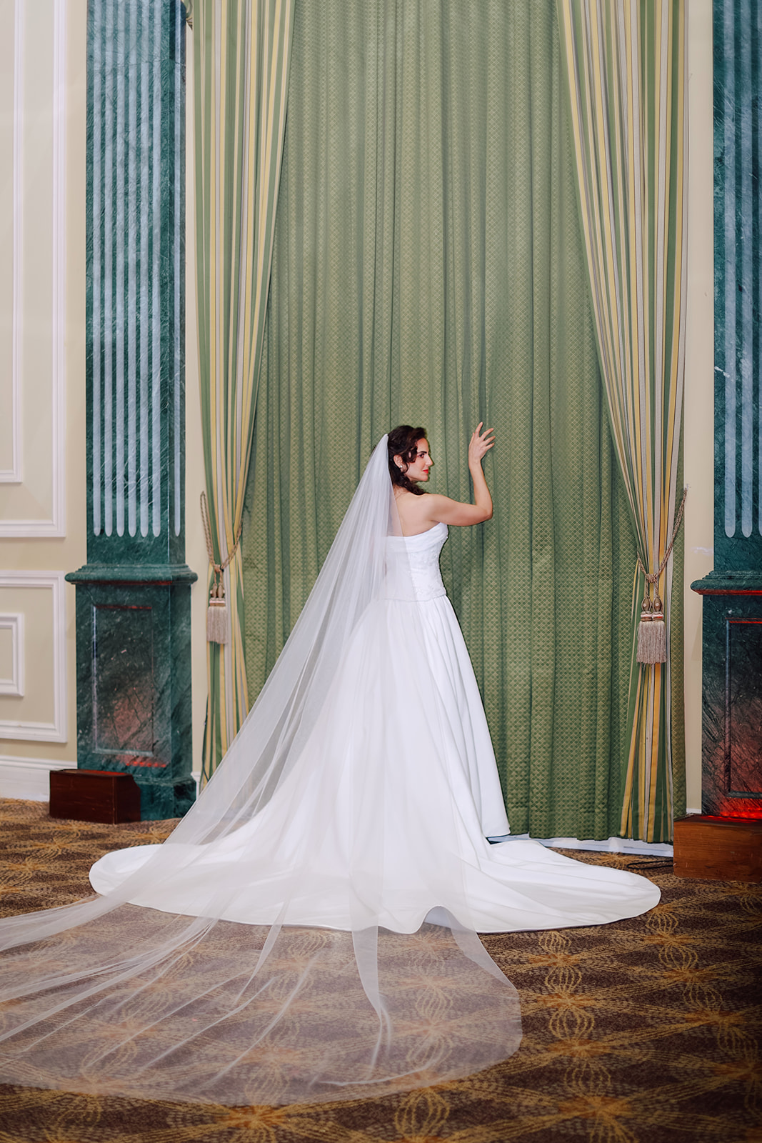 Back view of a luxurious satin ballgown wedding dress with beaded floral corset and long cathedral veil.